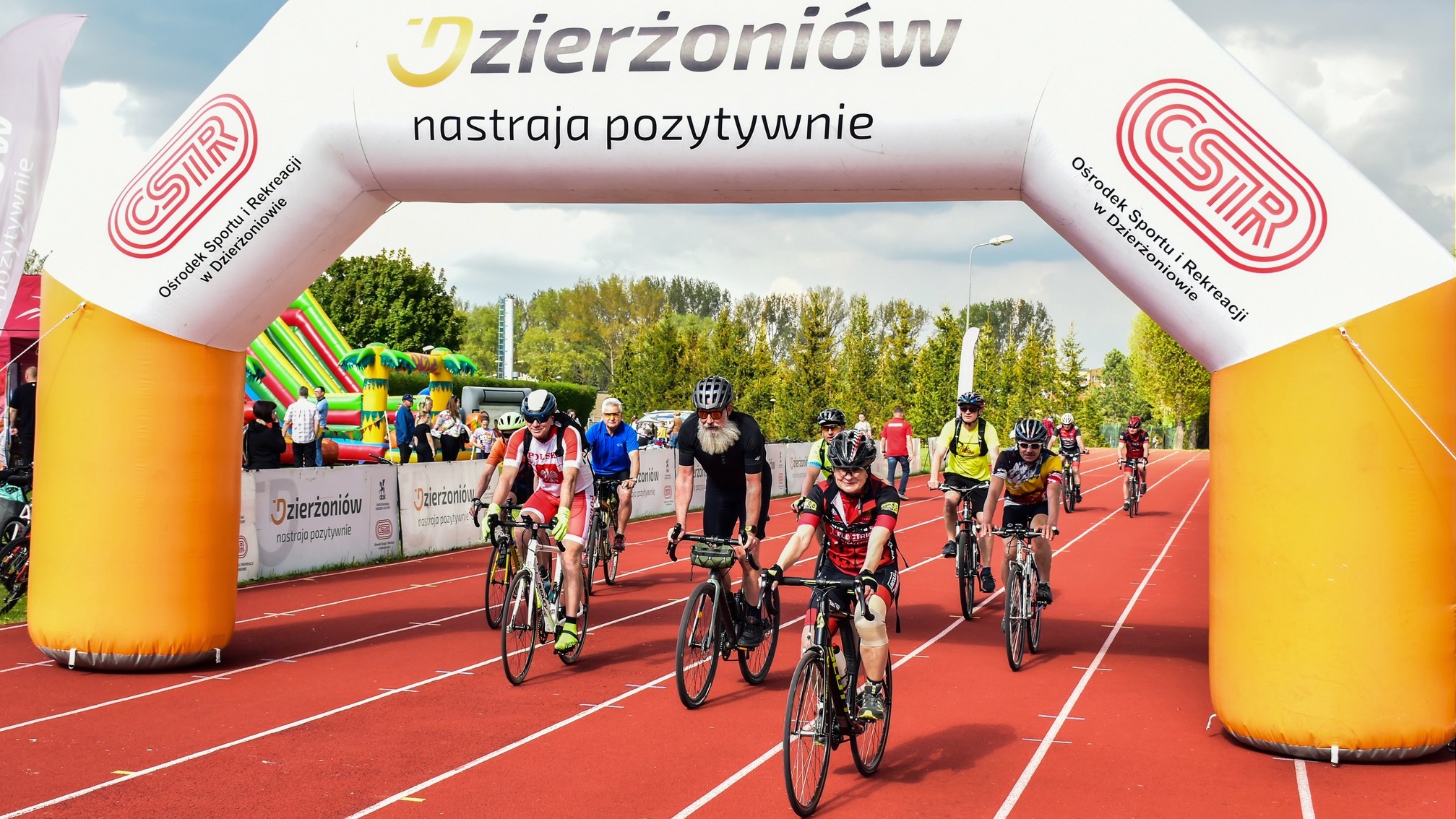 Grupa rowerzystów przejeżdzających przez metę ustawioną na bieżni