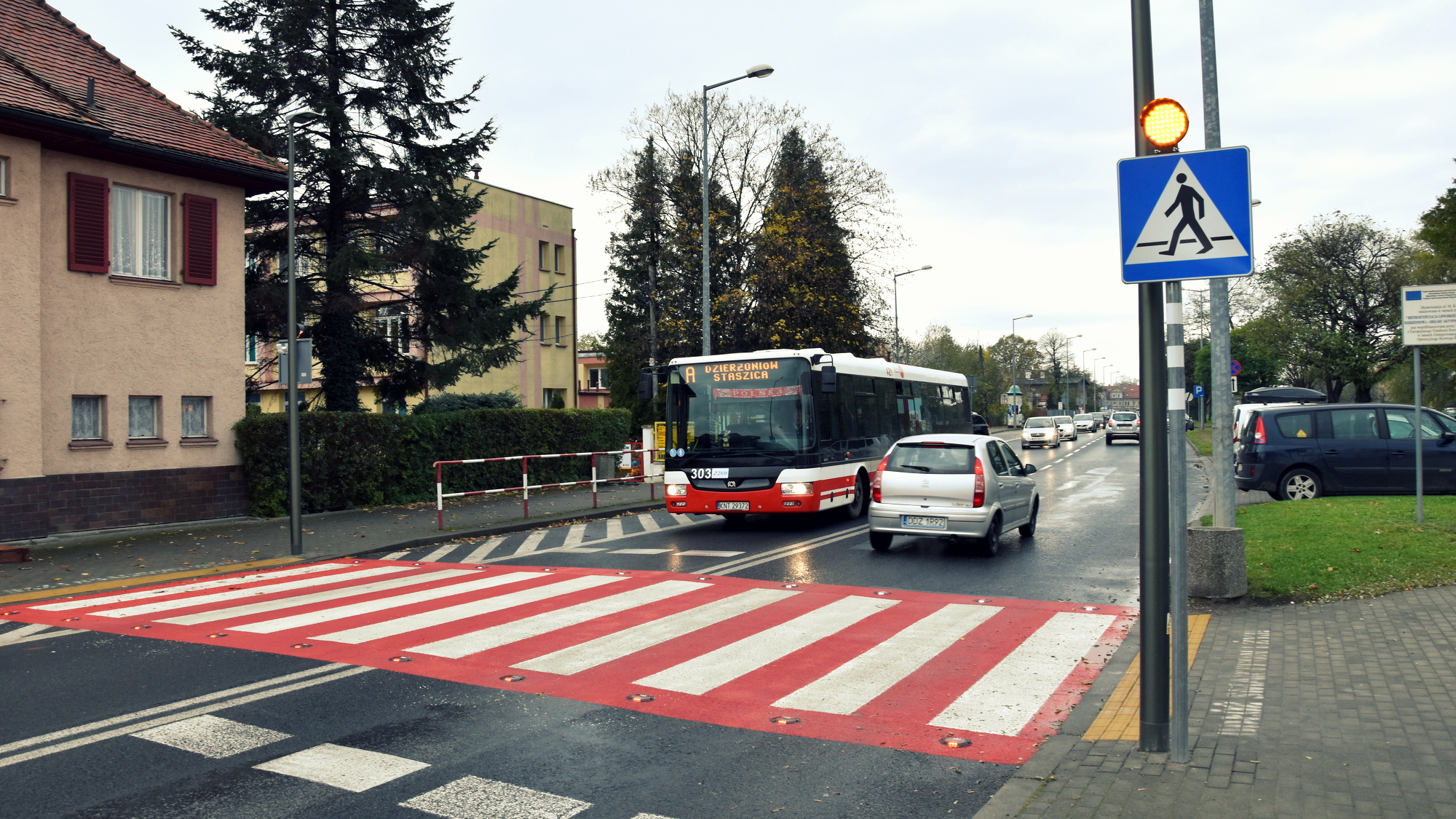 Czerwono-białem przejście dla pieszych, przed nim autobus komunikacji miejskiej