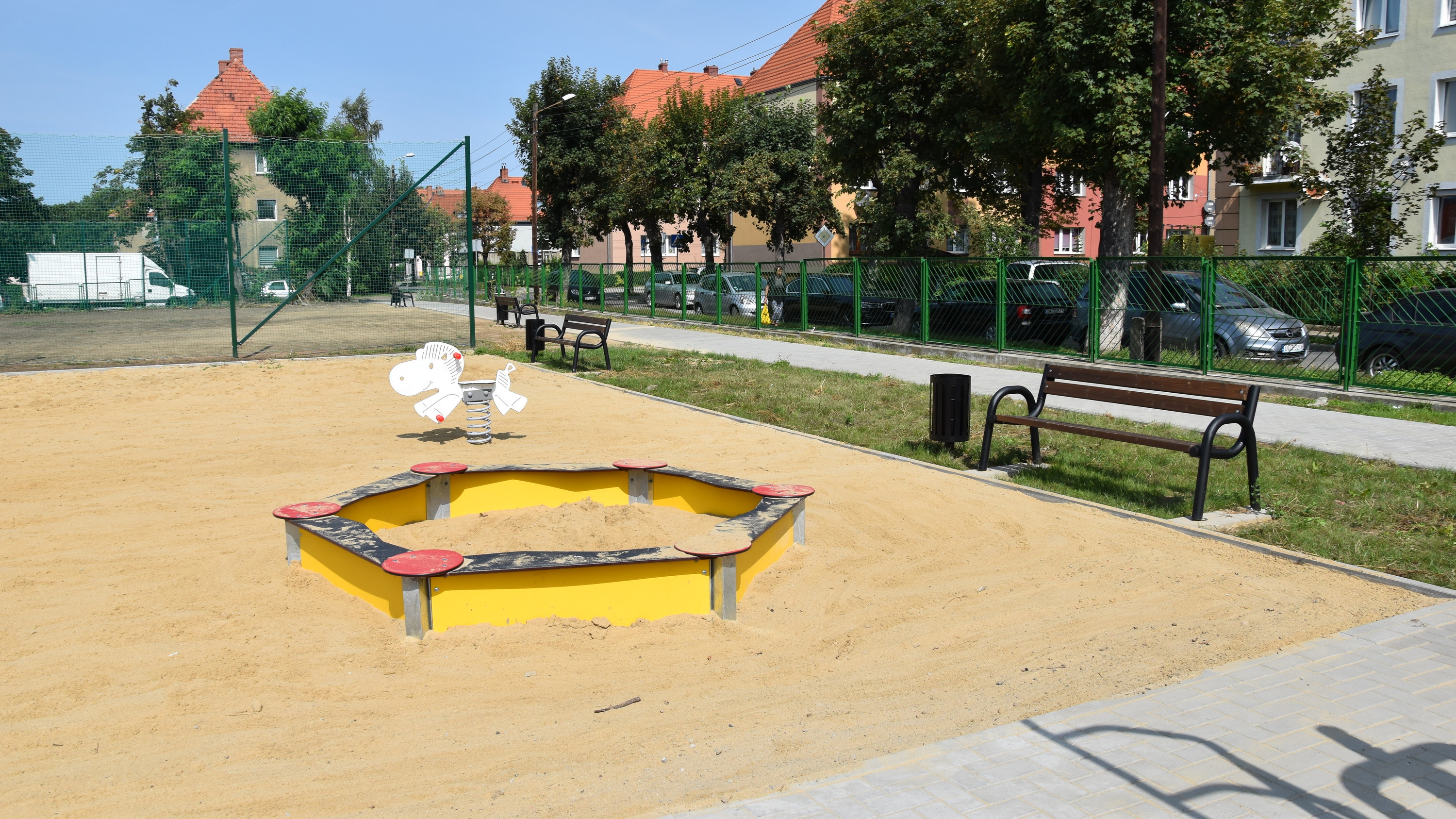 Plac zabaw, piaszczyste podłoże, obok ławki i chodnik