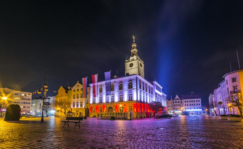 Budynek ratusza nocą podświetlonego iluminacją w biało-czerwone barwy