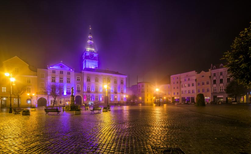 Dzierżoniów nocą, widok na zamglony rynek i ratusz w fioletowej iluminacji