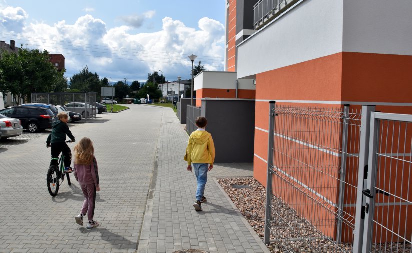 Dzieci przed wejśćiem do budynku, w drugim planie droga