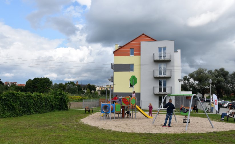 Plac zabaw z dziećmi przed budynkiem wielorodzinnym