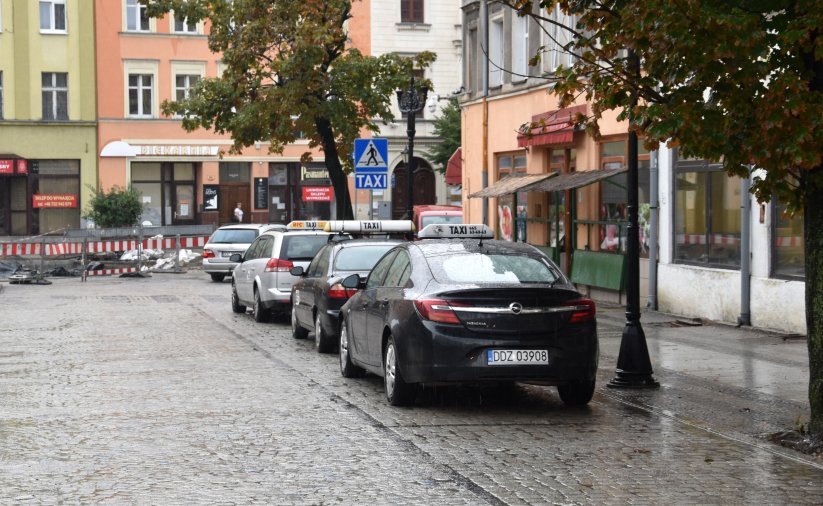 Trzy taksówki stojące na postoju w rynku, obok kamienice