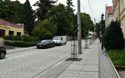 Stroma droga z kostki kamiennej widziana z dołu, po bokach zieleń