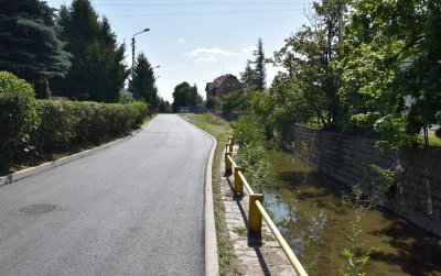 Ulica Żeromskiego z nowo wylanym asfaltem, po prawej stronie kamienne koryto rzeki