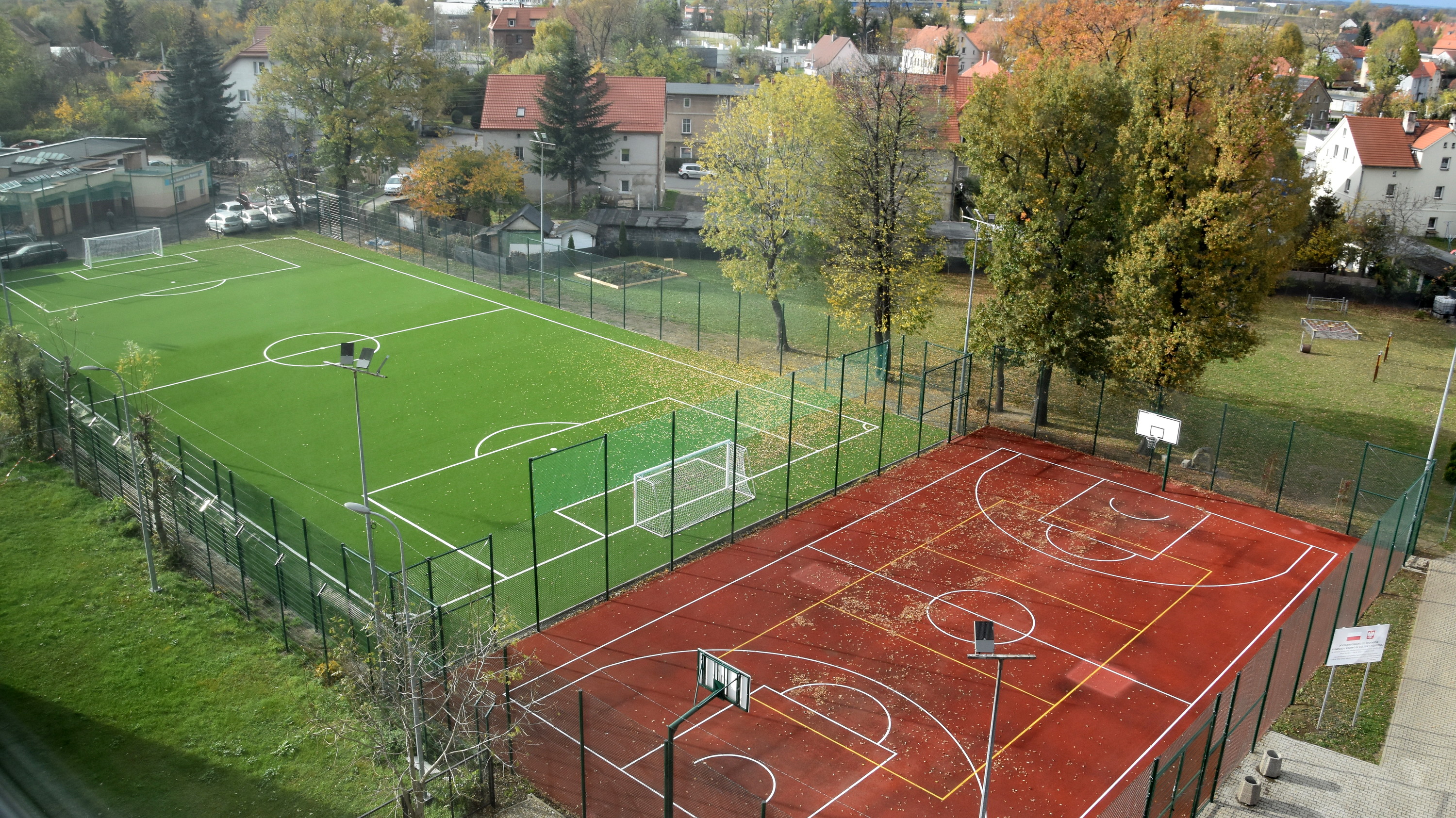 Boiska orlika z góry, zieloe boisko piłkarskie ze sztuczną nawierzchnią trawiastą i czerwone bosiko wielofunkcyjne