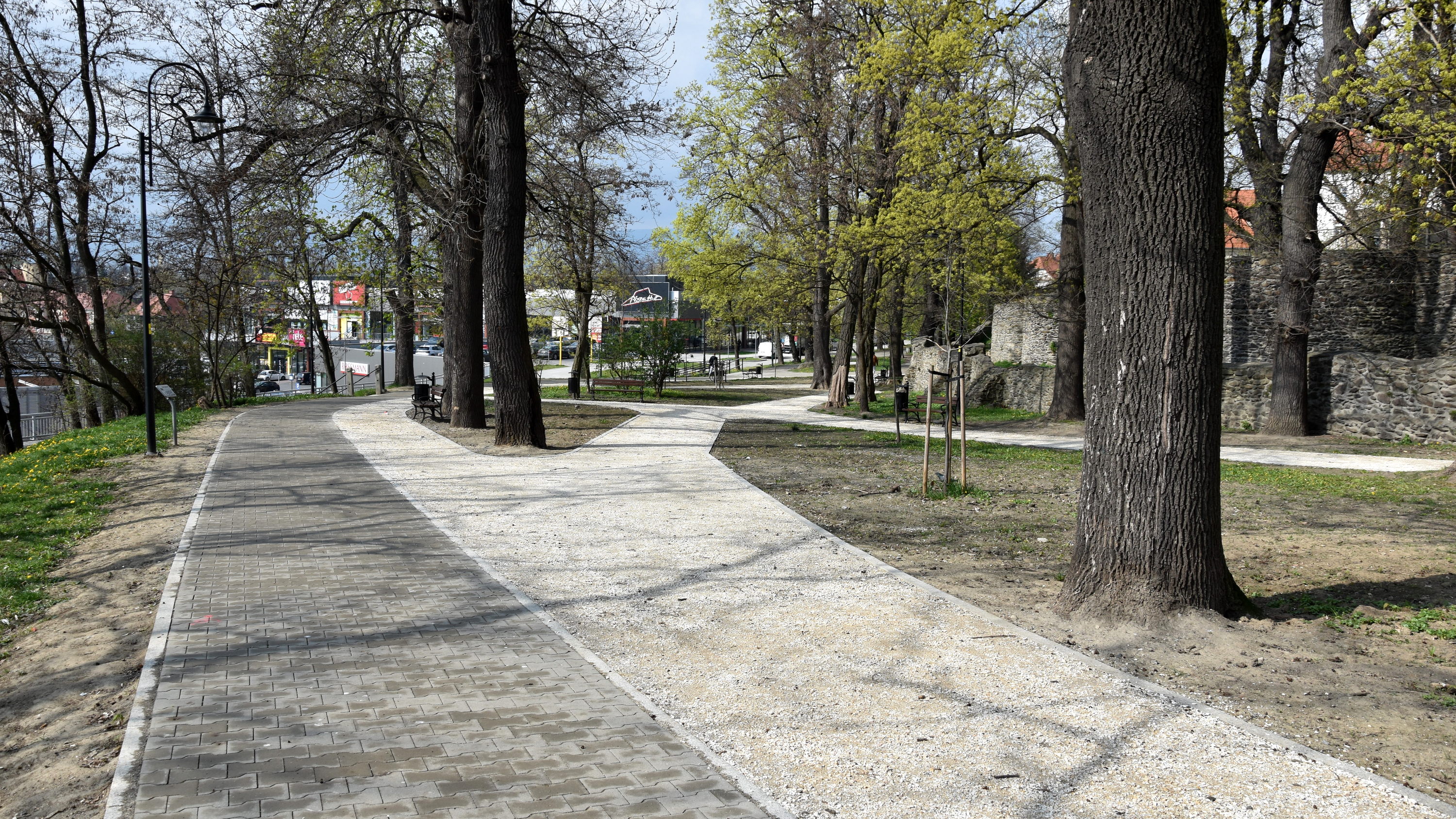 Nowe alejki w parku miejskim, po prawej wysokie kamienne mury