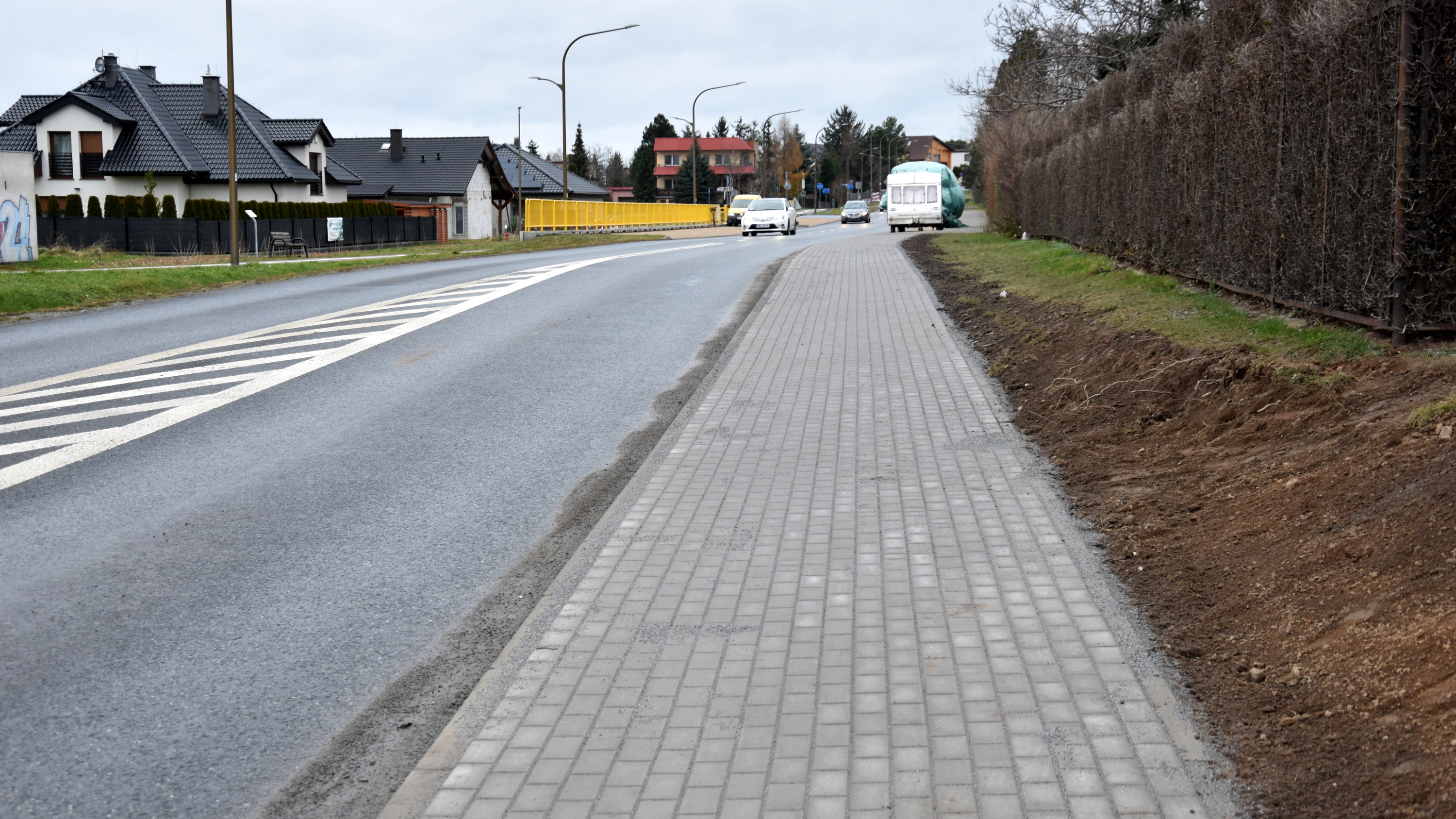 Droga, obok nowy chodnik z kostki betonowej, po lewej stronie dom jednorodzinny