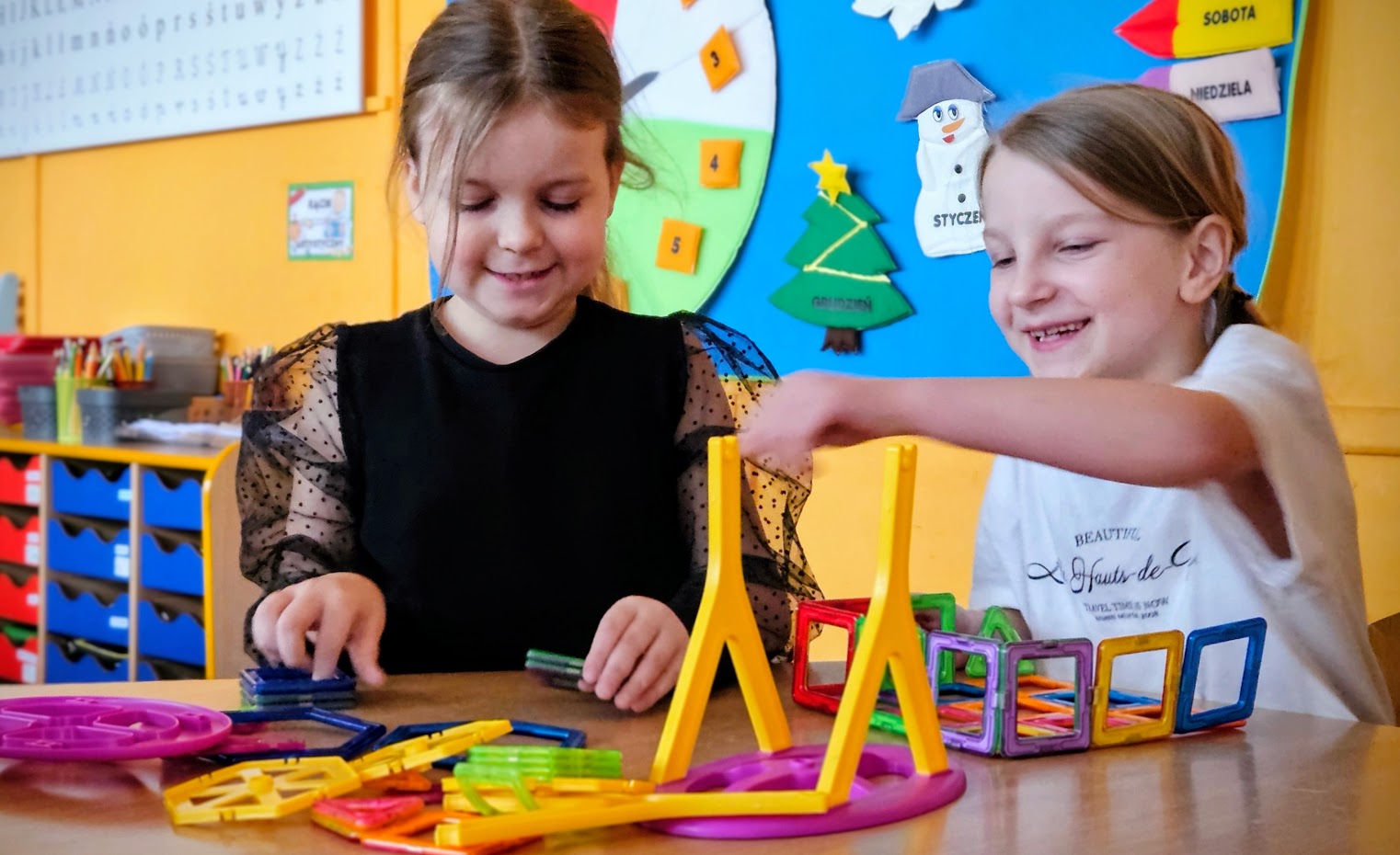 dwie dziewczynki układające konstrukcje z plastikowych elementów