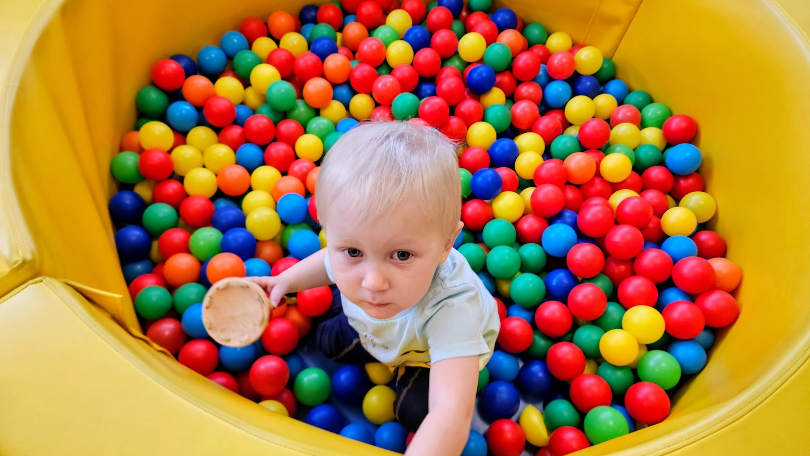 dziecko bawiące się w suchym basenie z kolorowymi piłeczkami