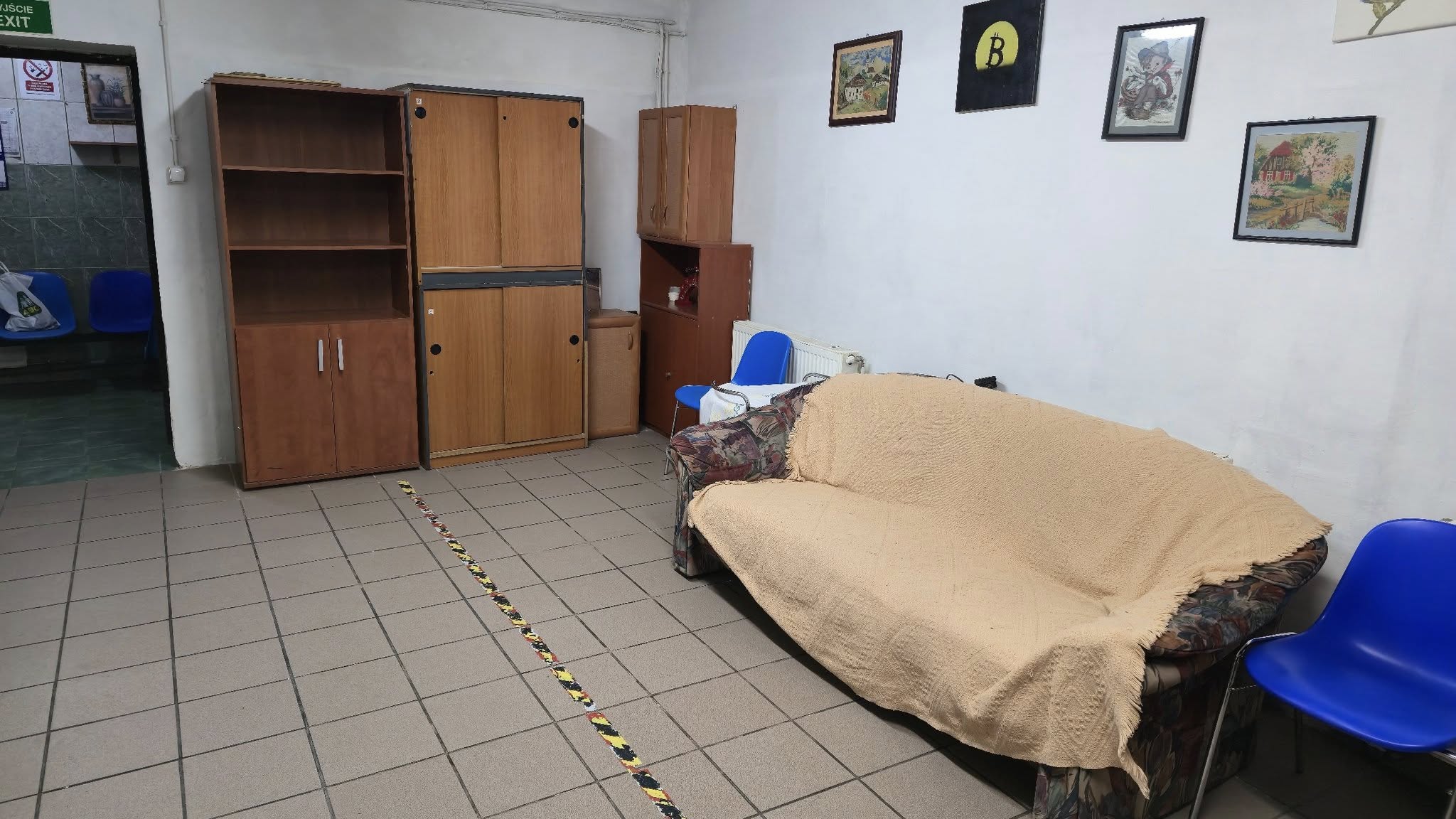 Pomieszczenie w ogrzewalni, sofa, szafki, na ścianach obrazki