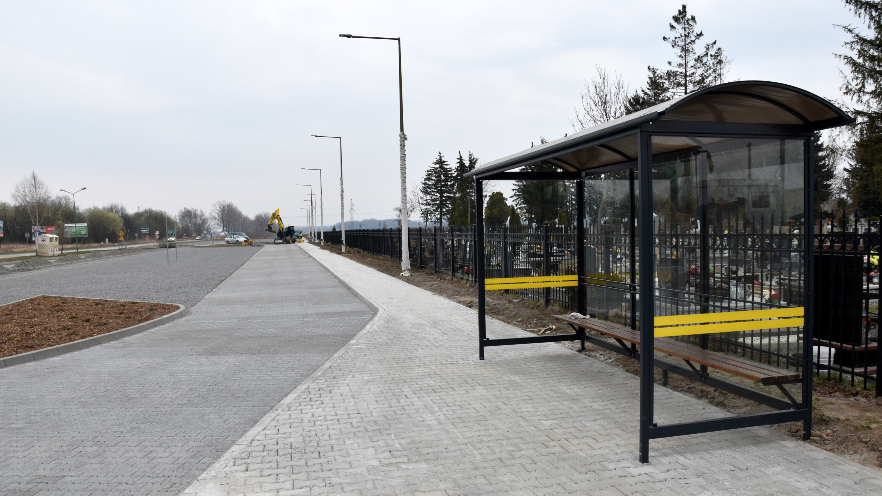 Duży parking przy cmentarzu, obok wiata przysatnkowa