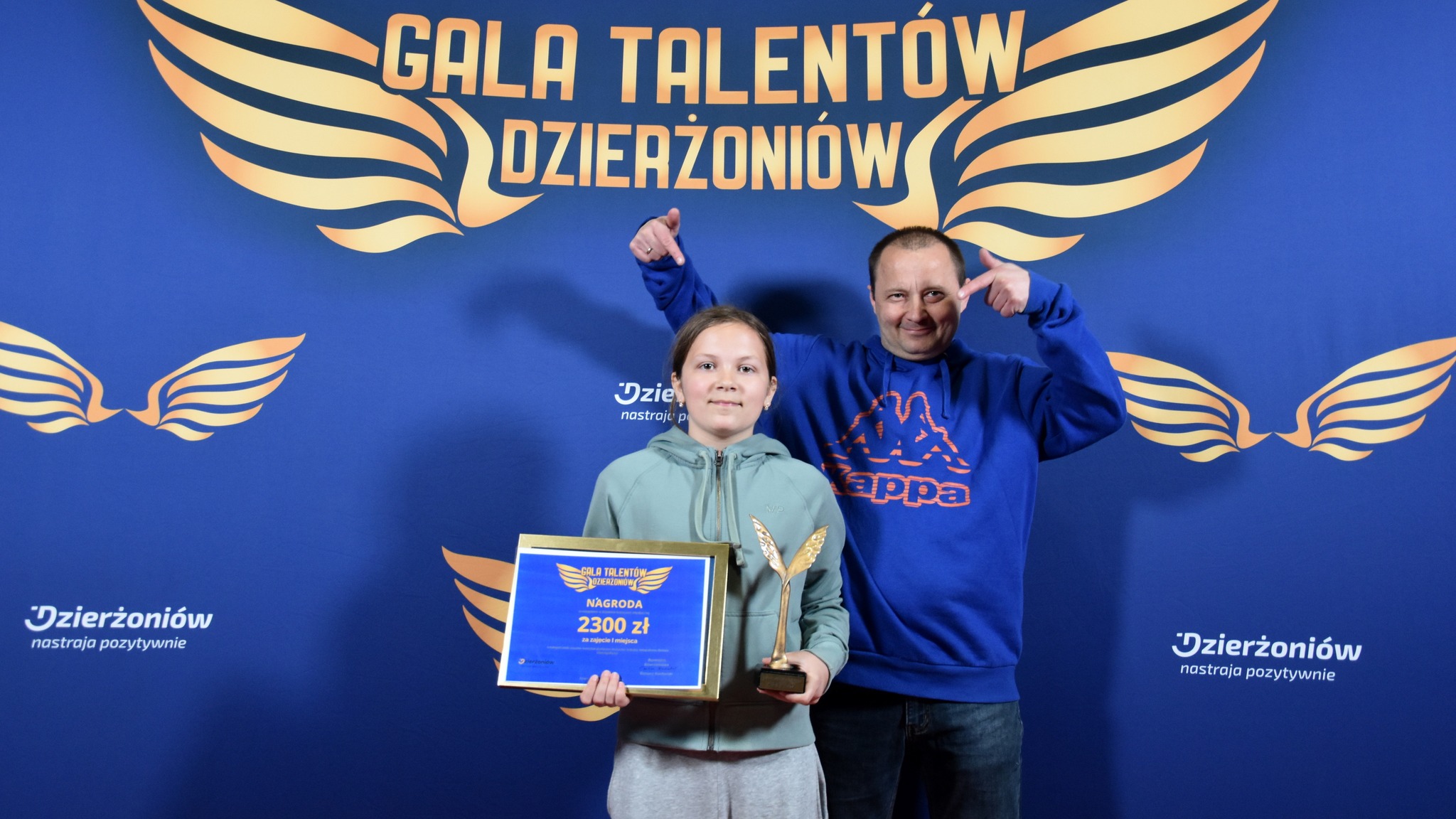 Alicja Ludwa ze statuetką, obok dumny tato, z tyłu napis Gala Talentów 