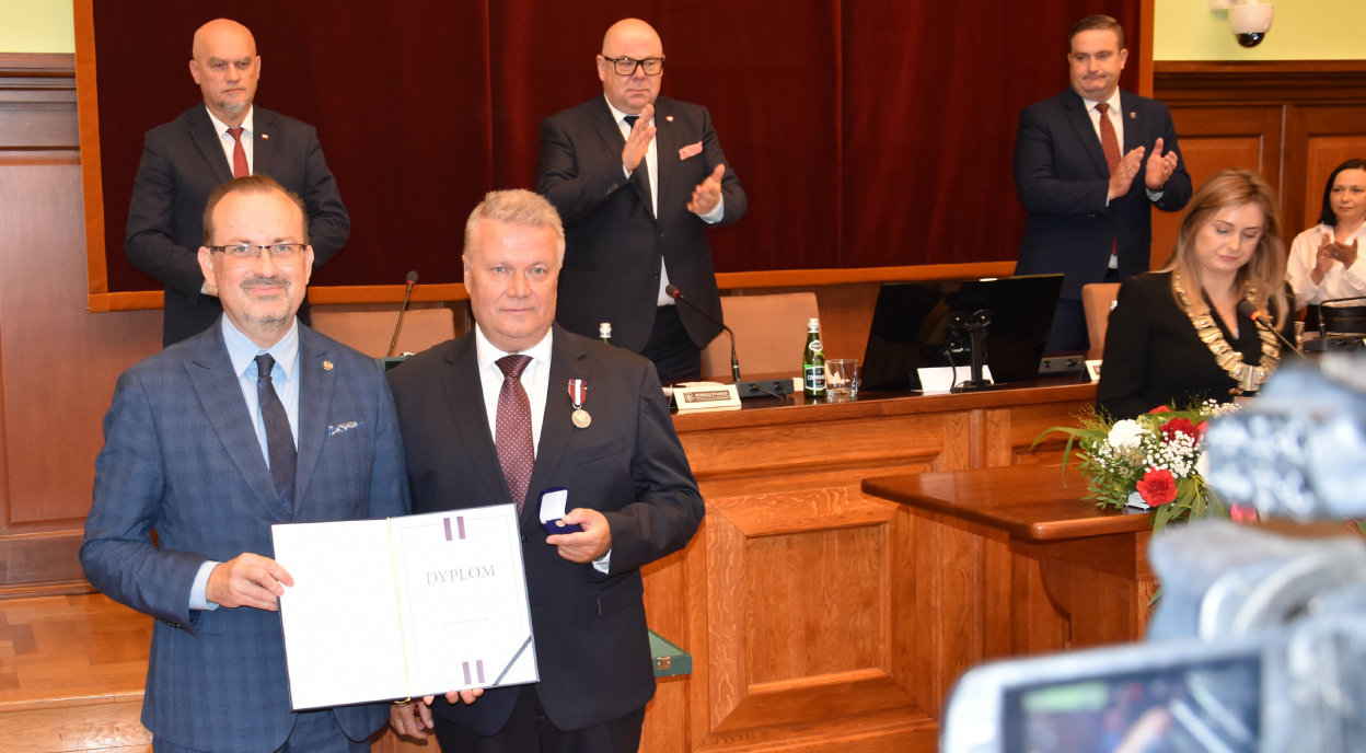 Burmistrz Dzierżoniowa odbiera odznaczenie, dookoła klaskający ludzie