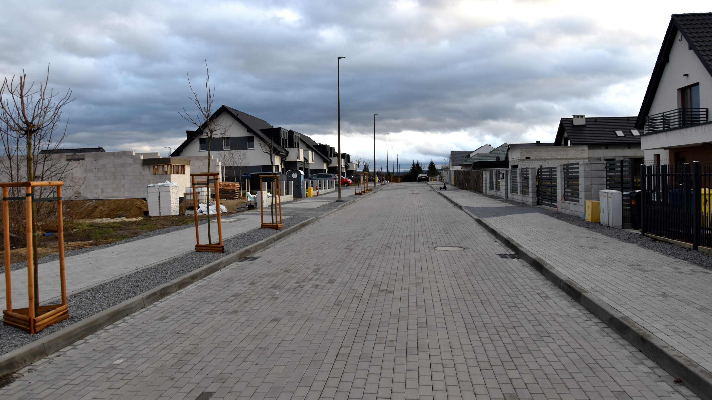 Droga z kostki betonowej, po bokach chodniki i domki jednorodzinne