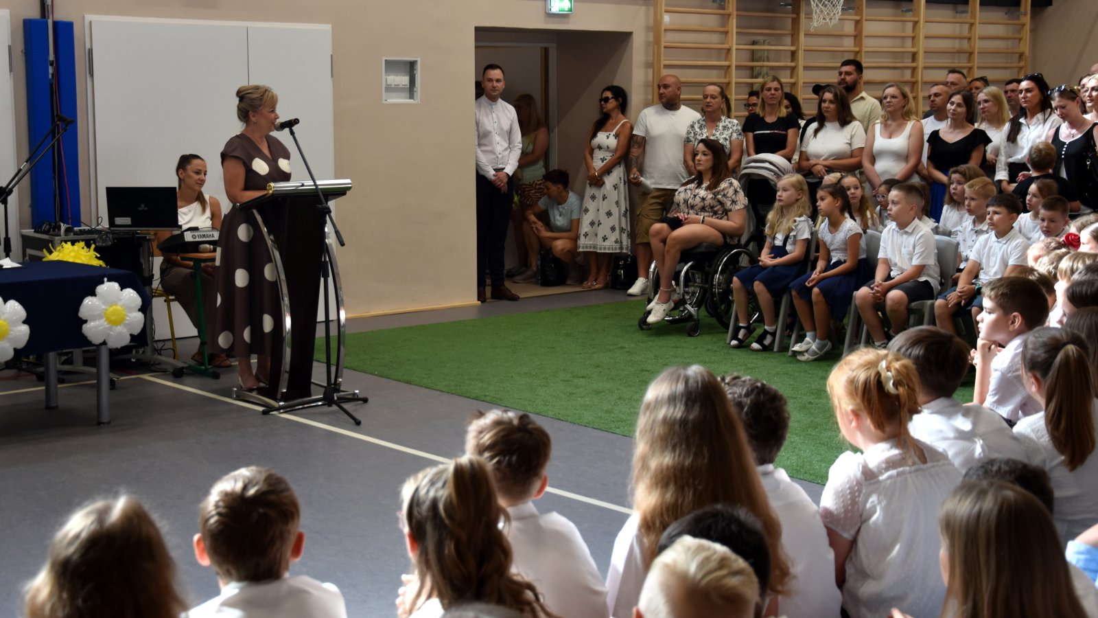 Zastępca burmistrza przy mównicy podczas zakończenia roku szkolnego