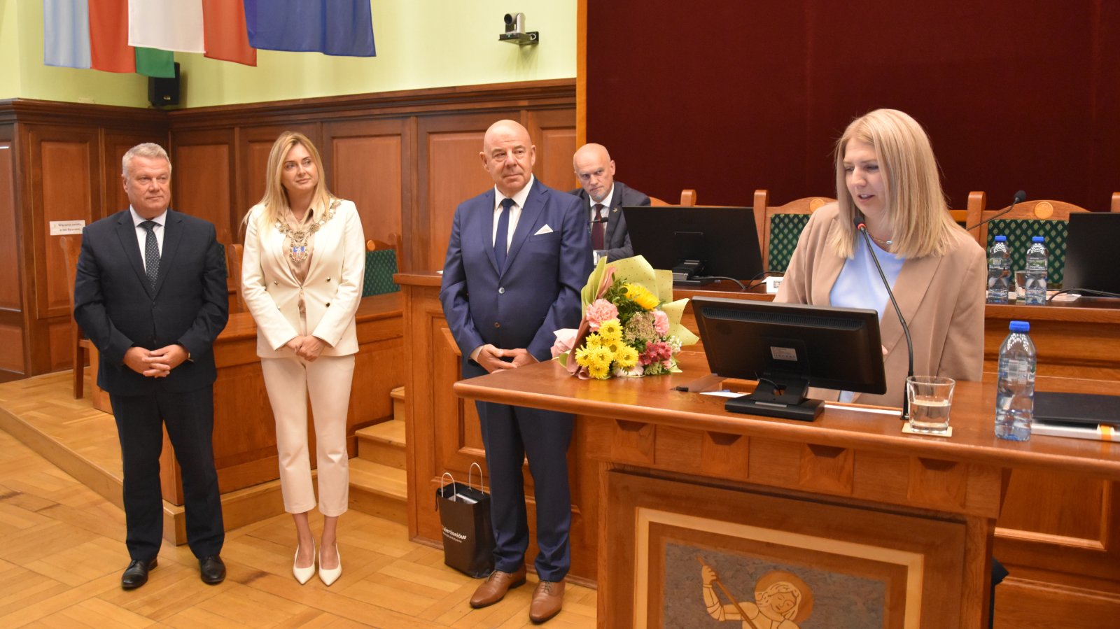 Justyna Kaczorowska przy mówinicy, obok burmistrz i dwójka radnych