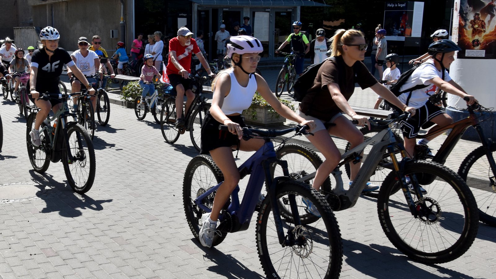Kilkanaście osób w różnym wieku jadących na rowerach
