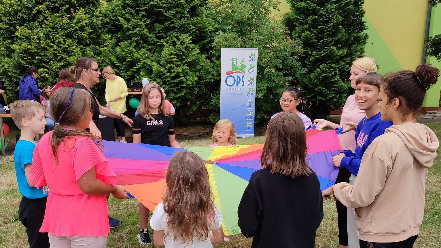 Dzieci trzymające okrągłą kolorową tkanianę