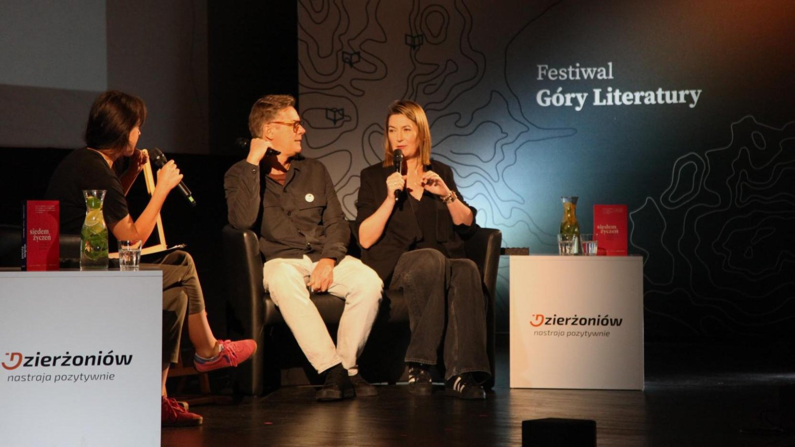 Dwie kobiety i mężczyzna siedzą i rozmawiają, z tyłu napis Góry Literatury