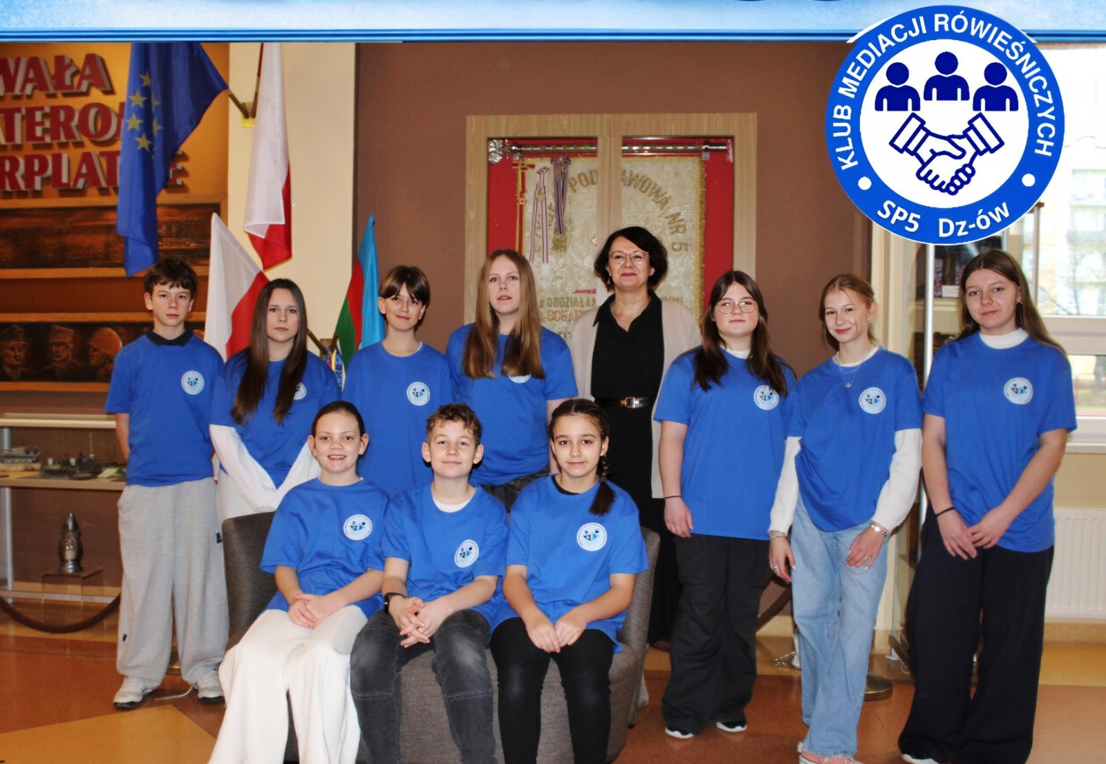 Grupawe zdjęćie uczniów w niebieskich koszylkach, w prawym górnym rogu lagotyp 