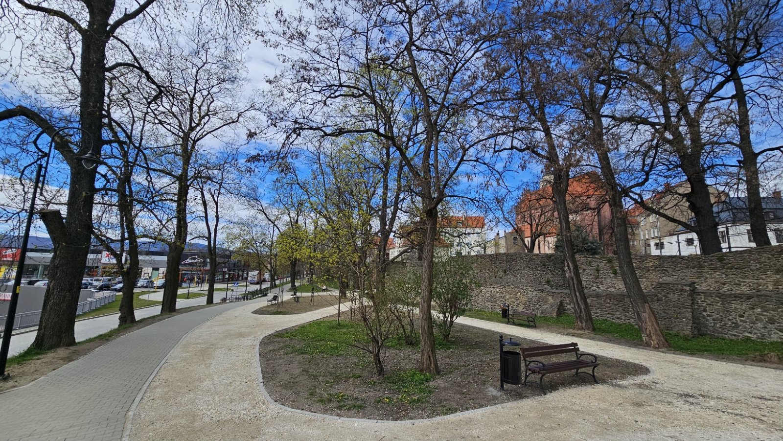 Park, po prawej zabytkowe mury, po lewej droga