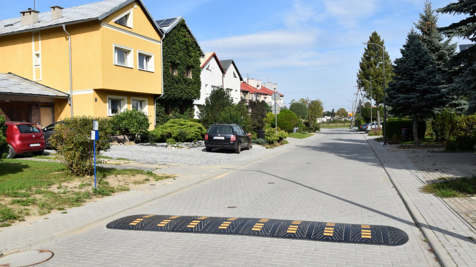 Nowa droga wewnątrz osiedla domków jednorodzinnych ułaożna z kostki betonowej. Na pierwszym planie spowalniacz drogowy