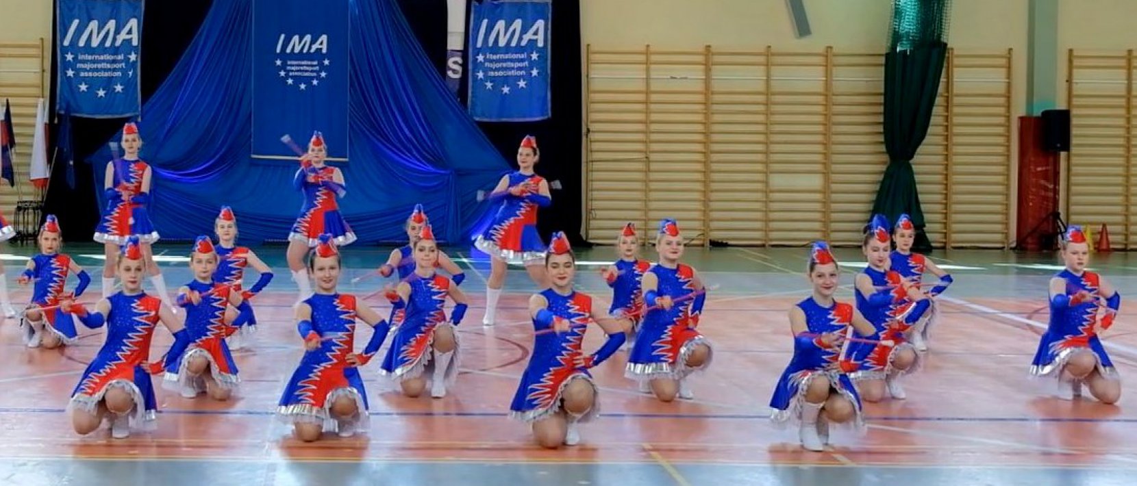 Mażoretki podczas występu w hali sportowej, zdjęcie grupowe