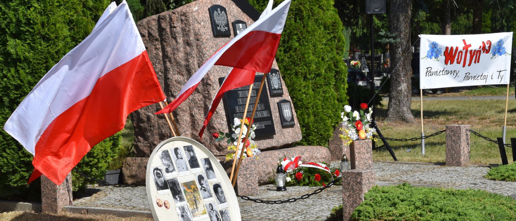Kamienny obelisk na cmentarzu, obo0k dwie flagi Polski