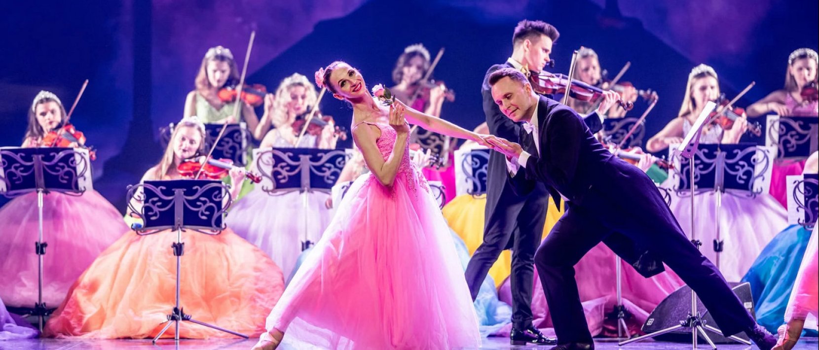 Fot: www.orkiestraksiezniczek.pl, dwoje tancerzy, za nimi skrzypaczki w kolorowych strojach