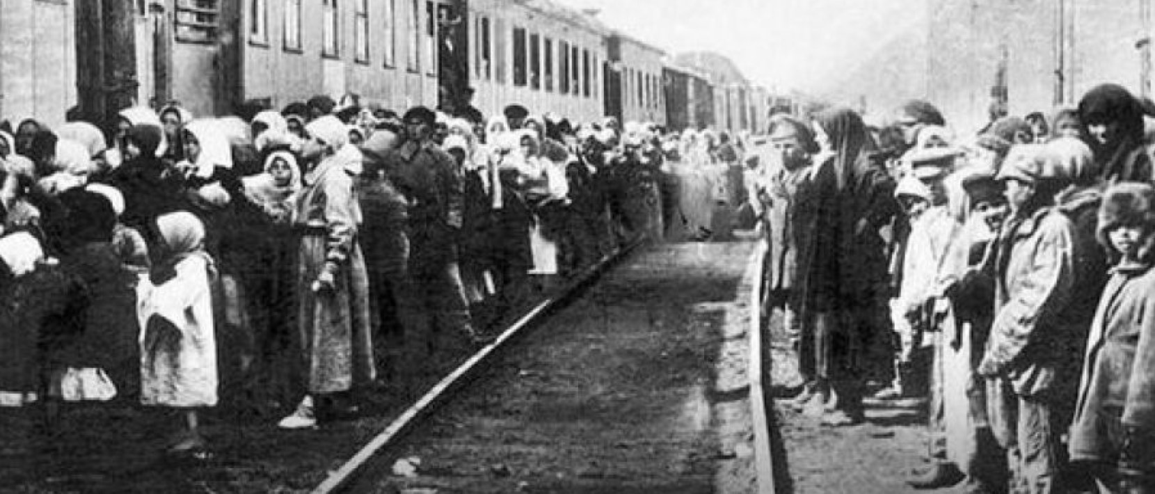 Zdjęcie archiwalne. Tłum osób stojących na torach przed wagonami kolejowymi