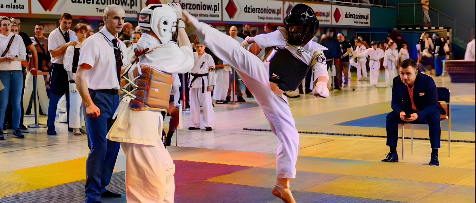 Dwóch karateków podczas walki, jeden w wyskoku atakuje nogą głowę przeciwnika