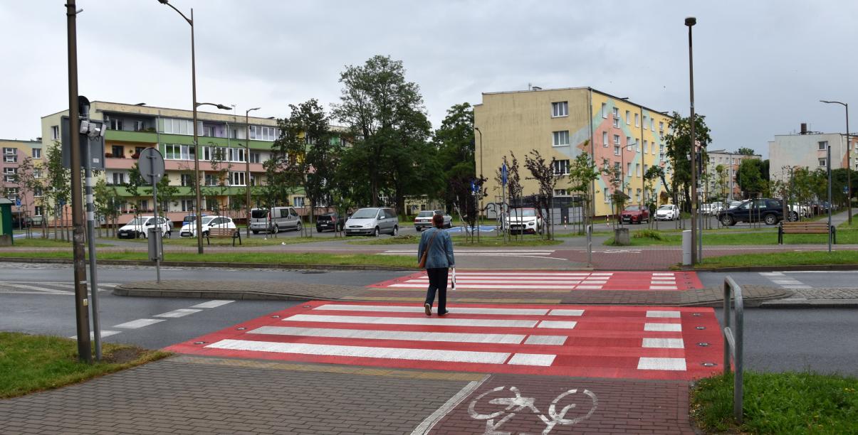 Widok przejścia aktywnego z przechodniem, na drugim planie budynki os. Kolorowego