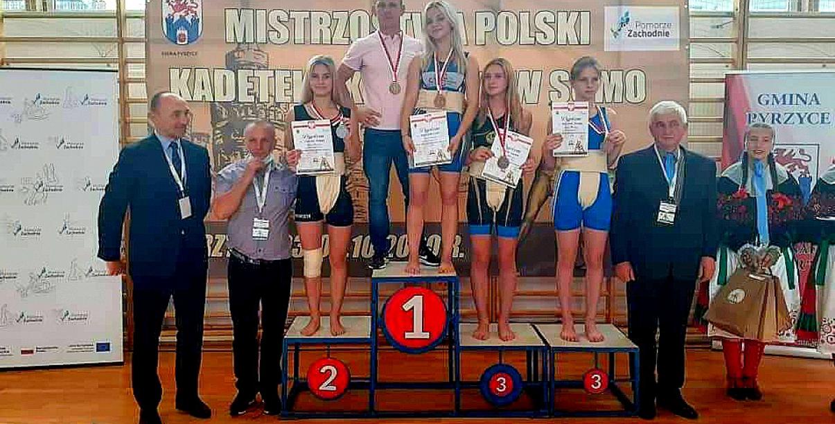 Zawodniczki z trenerami na podium medalowym