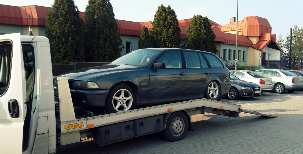 Auto stojące na lawecie, w drugim planie budynek