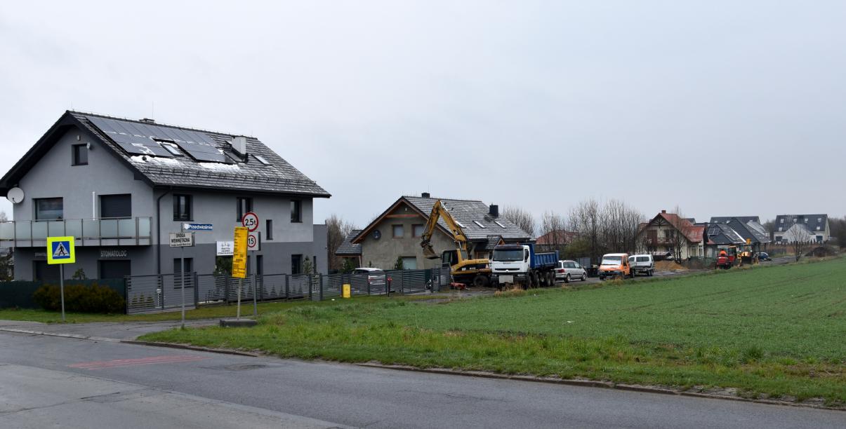 Widok na domy jednorodzinne i maszyny budowlane pracujące na drodze 