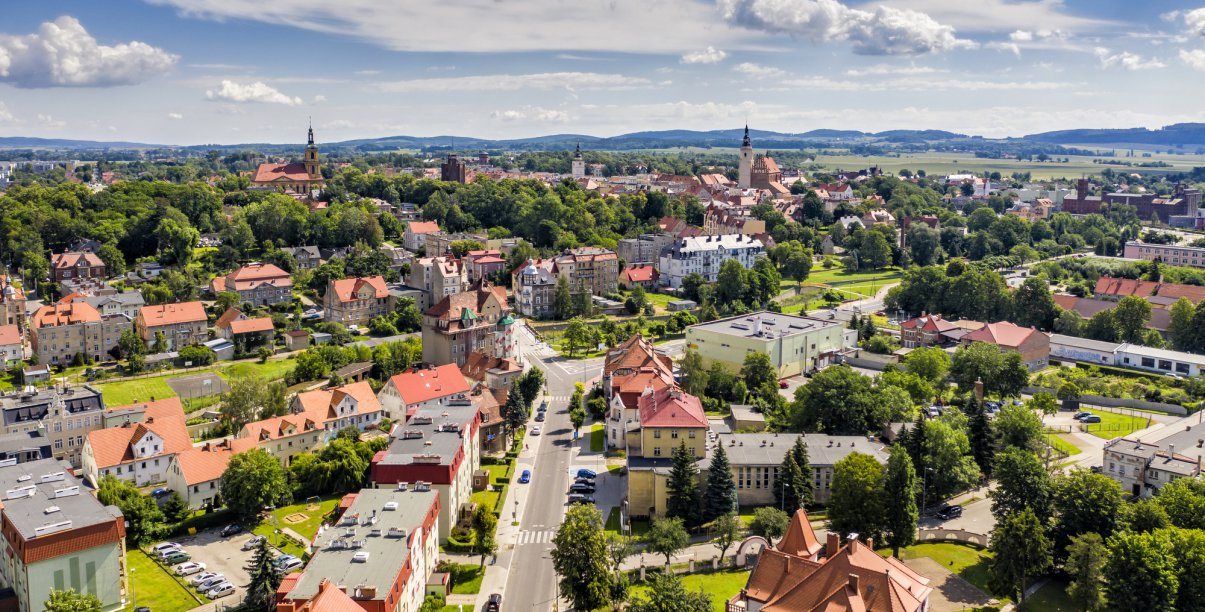 Dzierżoniów z górym, zachmurzone niebo, w drugim planie góry