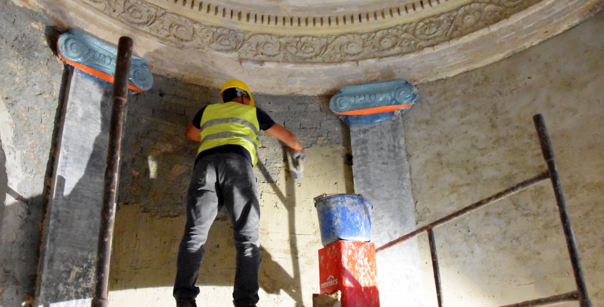 Wnętrze kaplicy, pracownik na rusztowaniu pracuje przy odestaurowaniu ściany