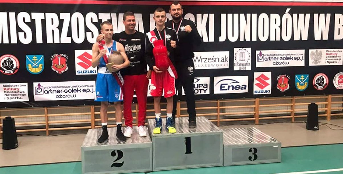 Dwóch zawodnikow i trenerów na podium