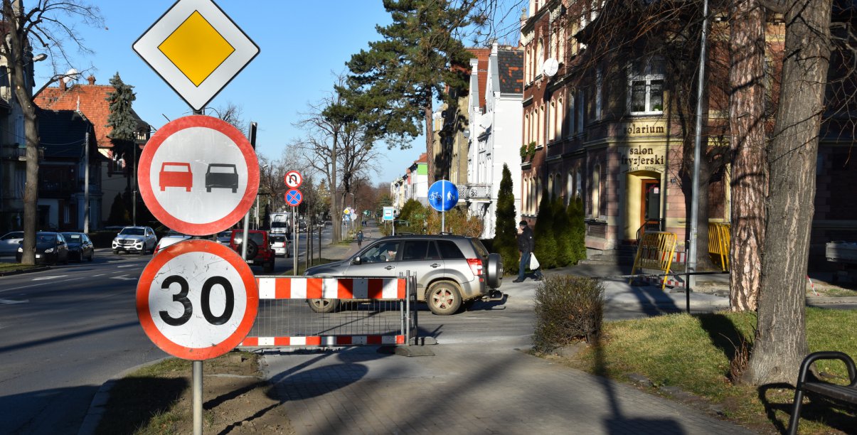 Widok chodnika i drogi, na pierwszym planie znaki drogowe