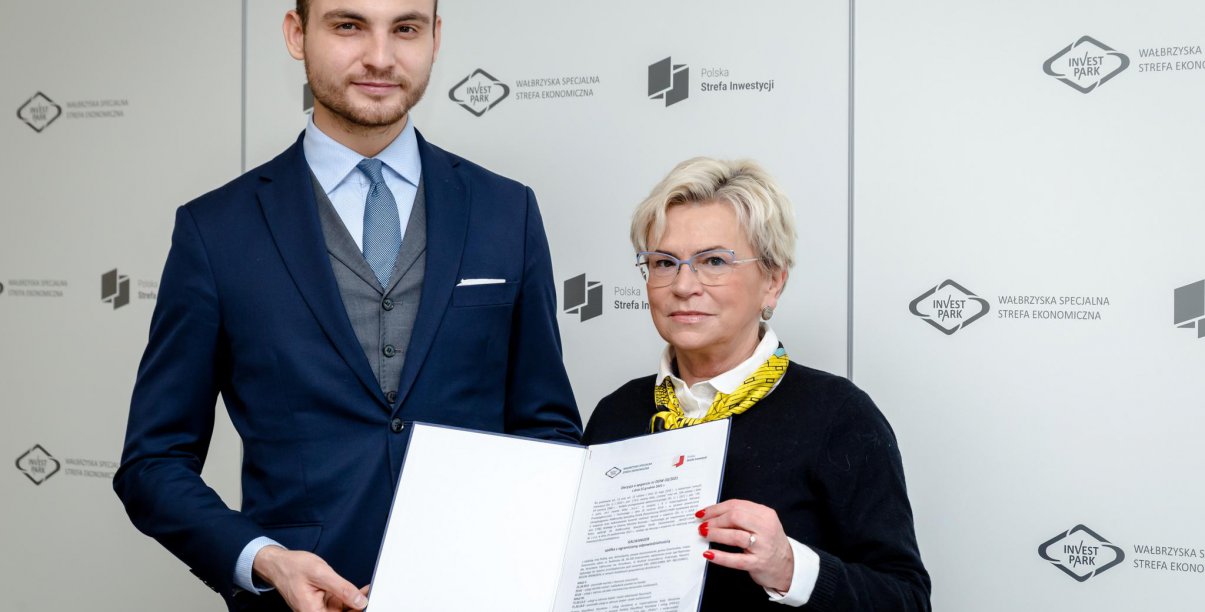 KObieta i mężczyzna trzymaja teczkę z dokumentami na tle ścianki Invest Park