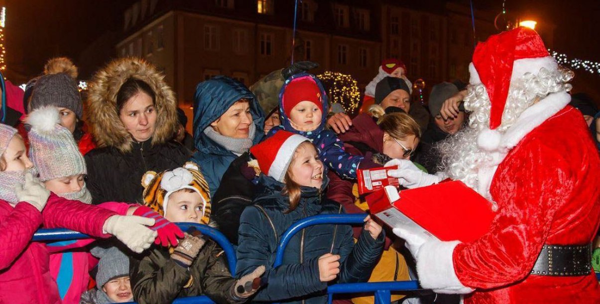 Mikołaj otoczony dziećmi rozdaje prezenty. Noc.