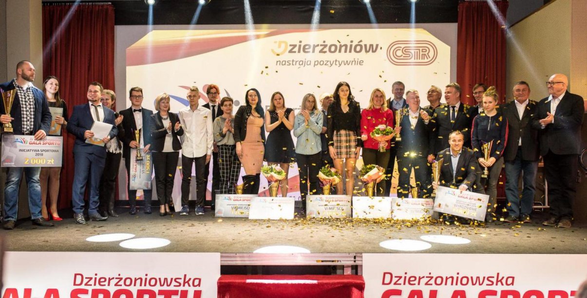 Grupowe zdjęcie kilkunastu sportowców na scenie