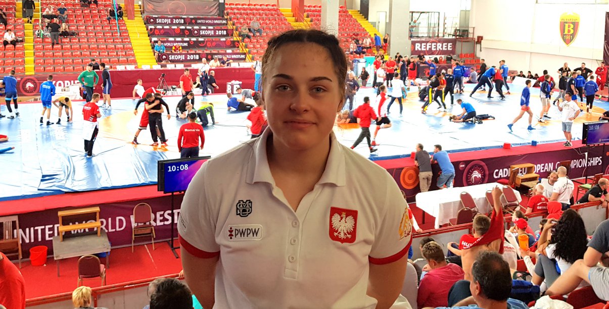 Dziewczyna w białej koszulce i Godłem Polski, w drugim tle wnętrze hali sportowej