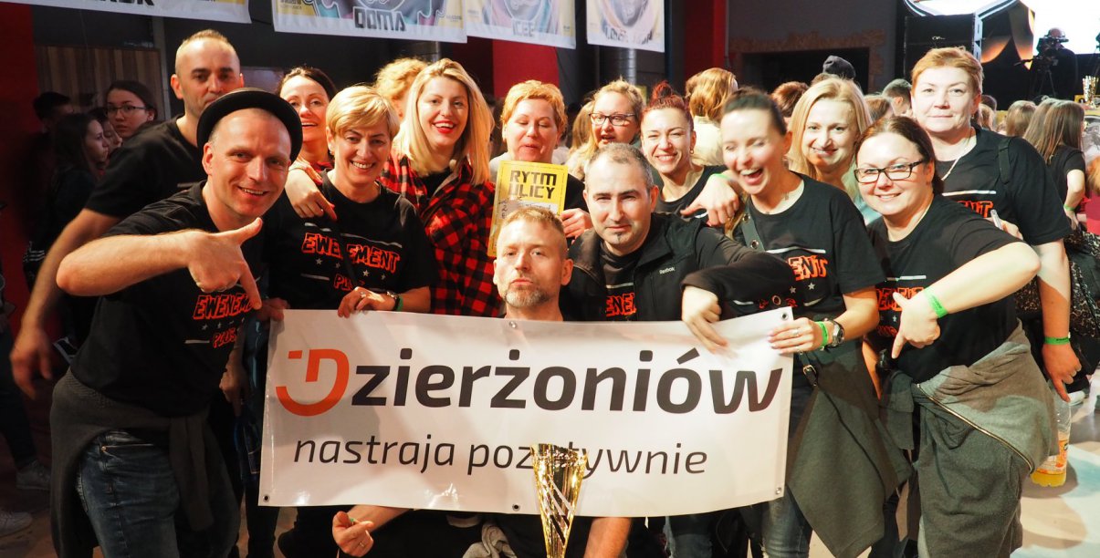 Usmiechnięta grupa trzymająca baner z napisem Dzierżoniów nastraja pozytywnie