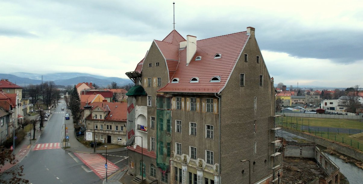 Zabytkowa komienica widziana z góry, w drugim tle miasto i góry