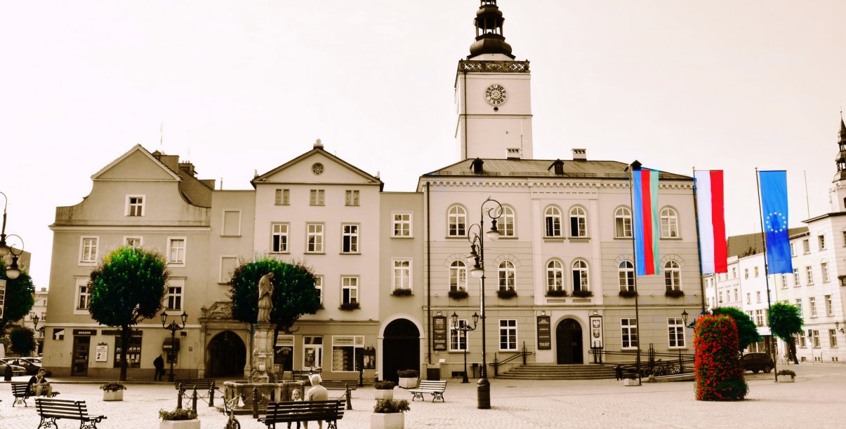 Rynek i widok dzierżoniowskiego ratusza, obok flaga Polski, Unii Europejskiej i miasta