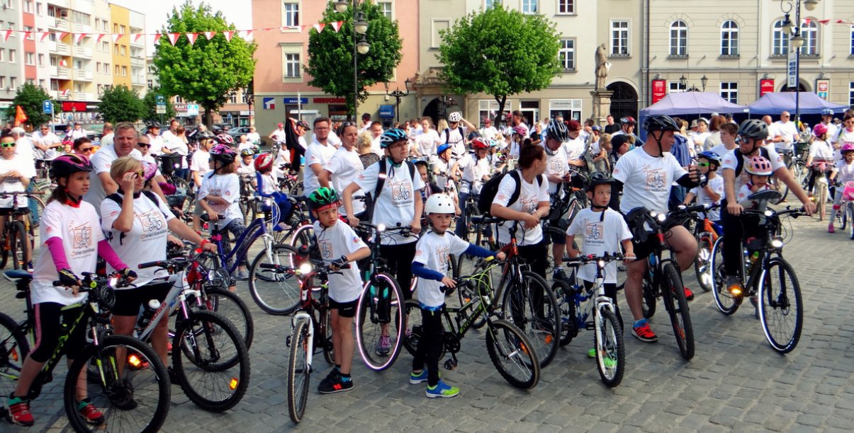 Duża grupa dorosłych i dzieci z rowerami na rynku