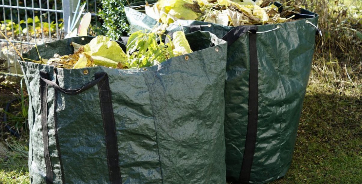 Dwie duże zielone torby tekstylne wypełnione odpadami zielonymi 